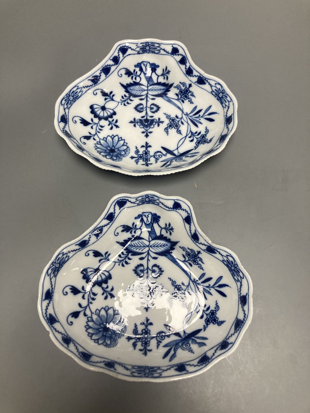 Two Meissen onion pattern shell-shaped dishes, width 19cm, and an English porcelain cabinet cup, inscribed in gilt, Think on me